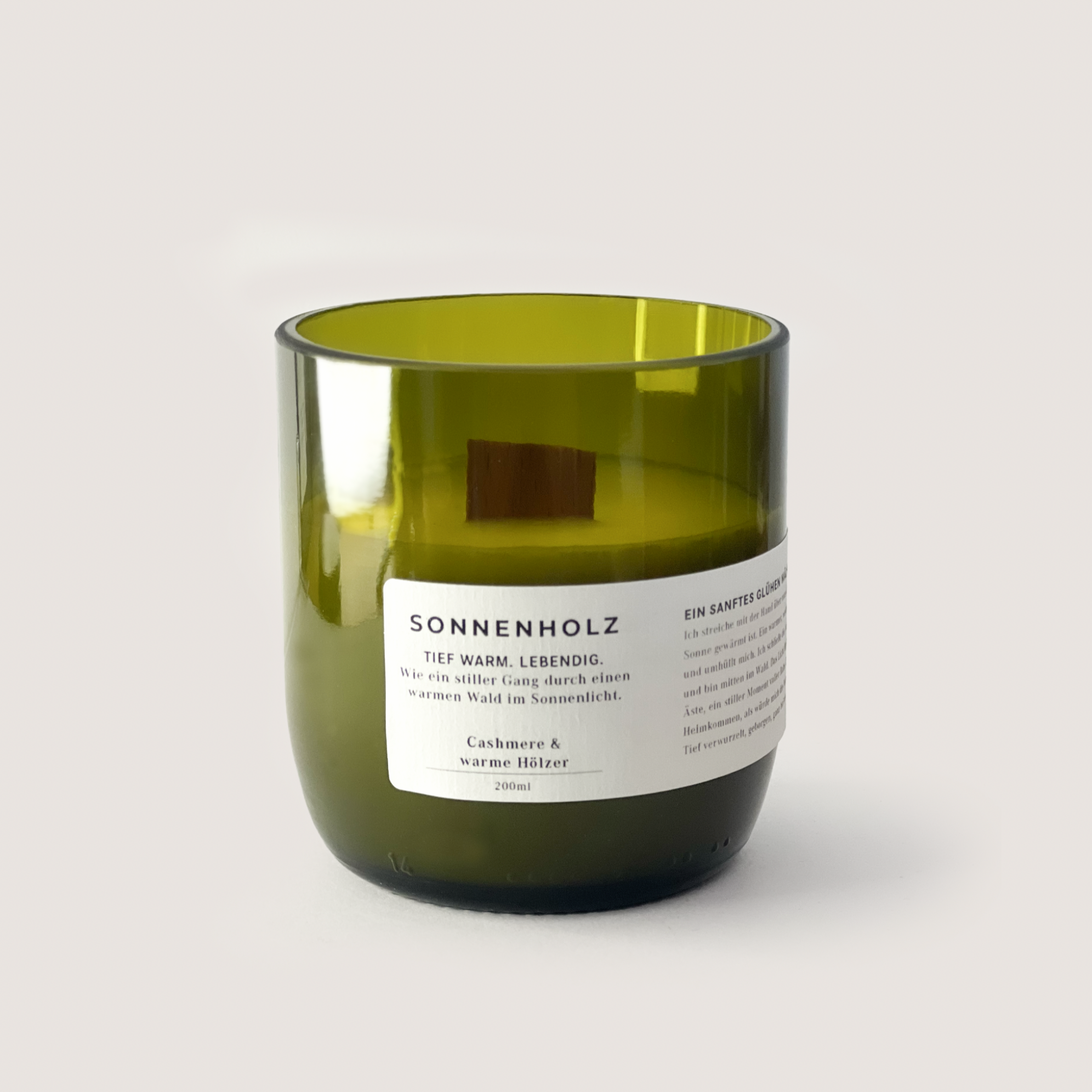Green glass candle labeled SONNENHOLZ 200ml with cashmere and warm woods scent.