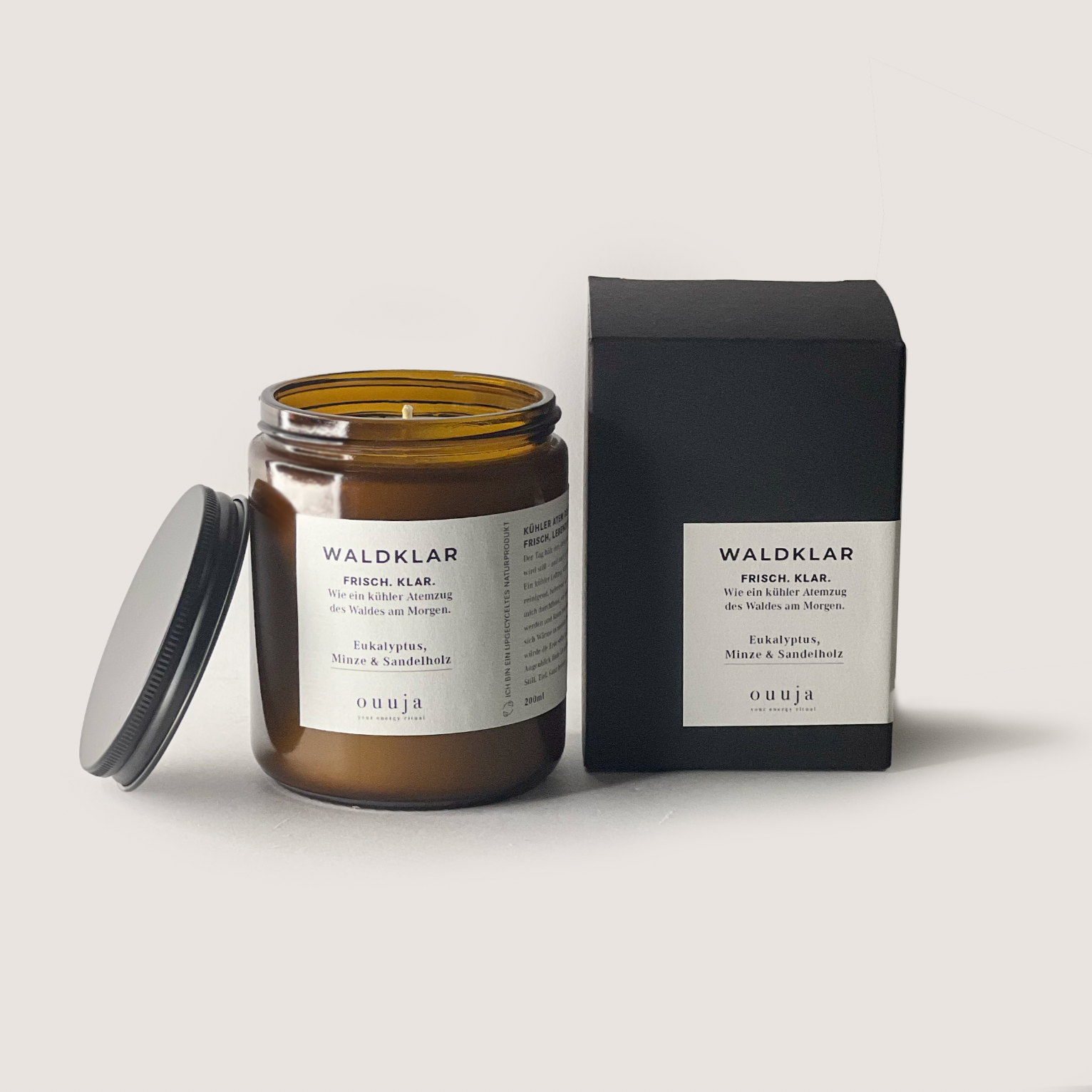 WALDKLAR Naturglas scented candle with eucalyptus, mint, and sandalwood in brown glass jar with black lid and matching black box.