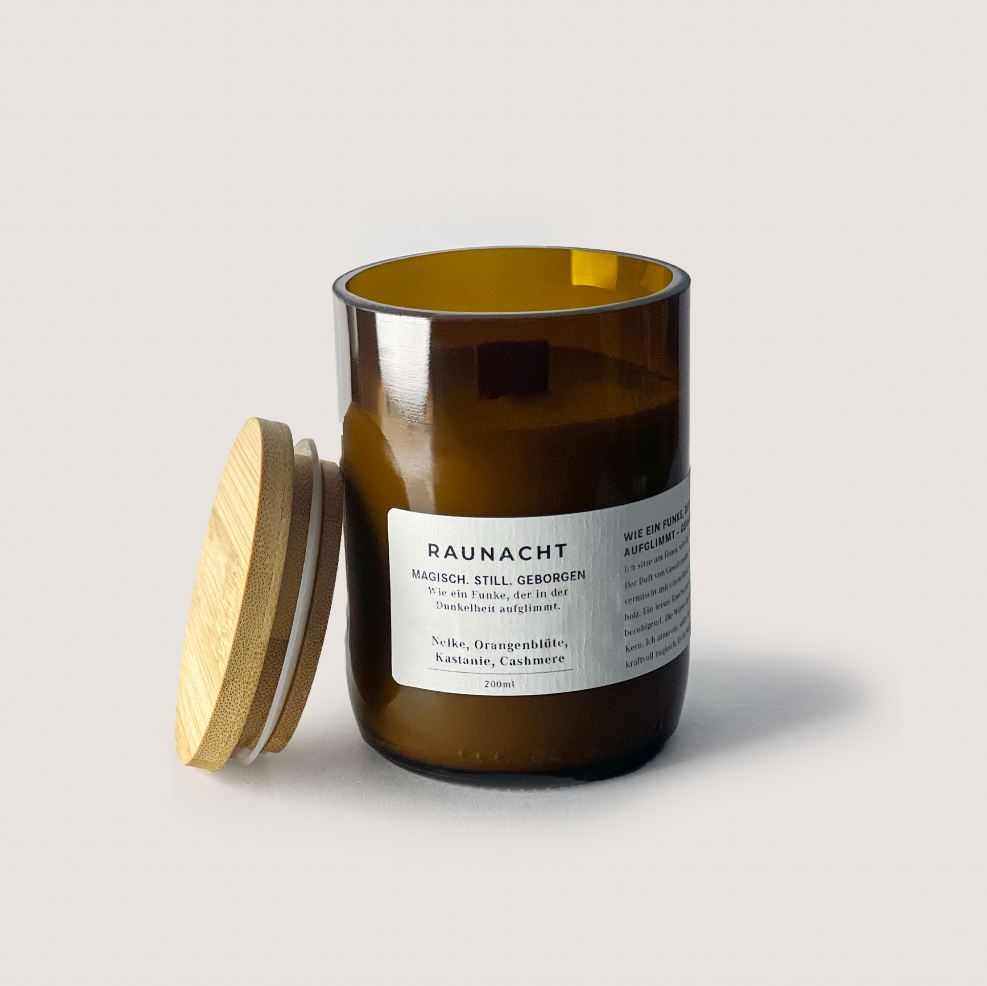 RAUNACHT 200ml scented candle with clove, orange blossom, chestnut, and cashmere fragrance in amber glass jar with wooden lid