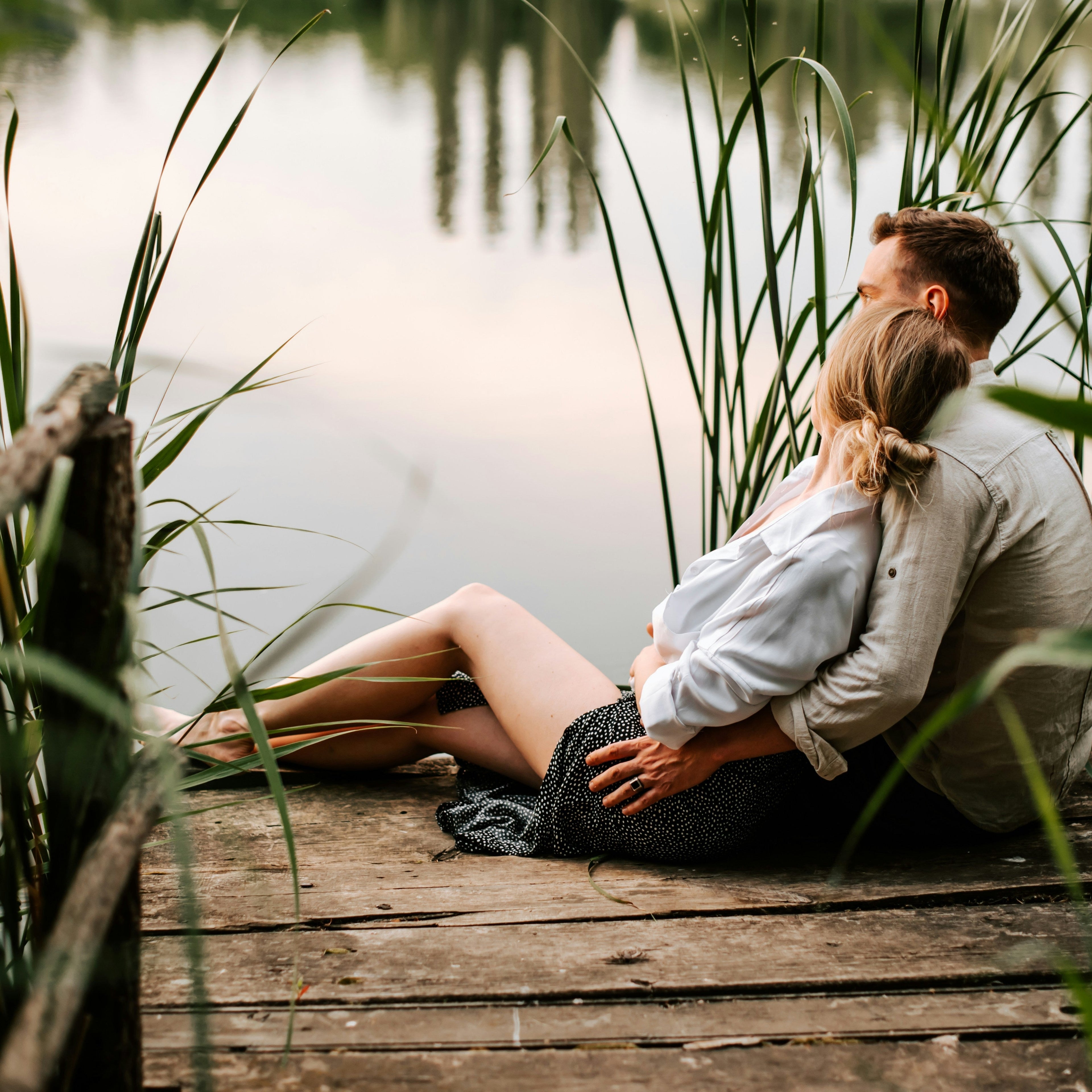 Paar entspannt am Seeufer in ruhiger Abendstimmung mit natürlicher Umgebung und Wasser im Hintergrund