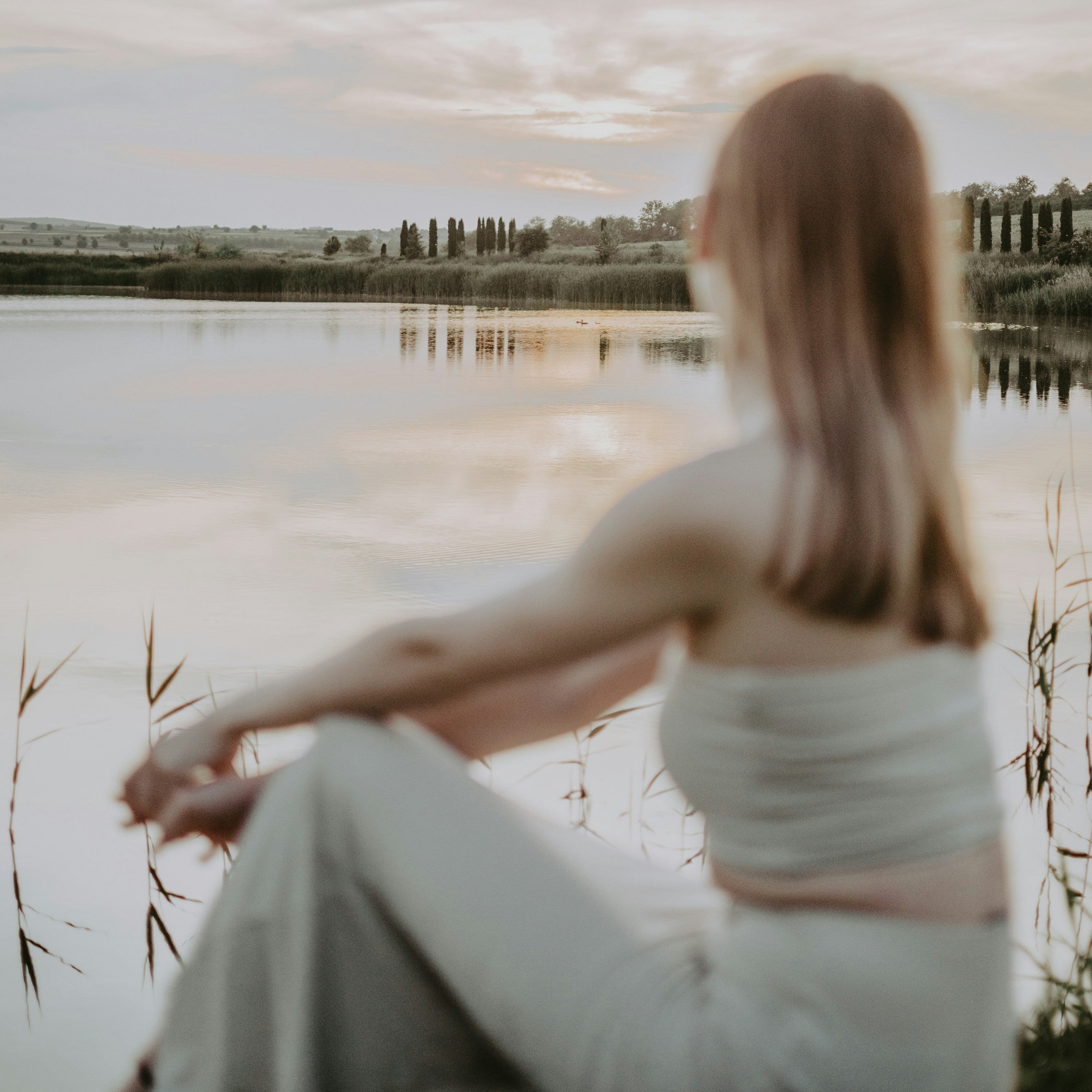 Frau entspannt am Seeufer bei Sonnenuntergang, symbolisiert frische, klare und spritzige Sommerwind-Stimmung mit Kräuter- und Zitrusduft, Rosmarin, Basilikum, Salbei, Orange und Lemon.